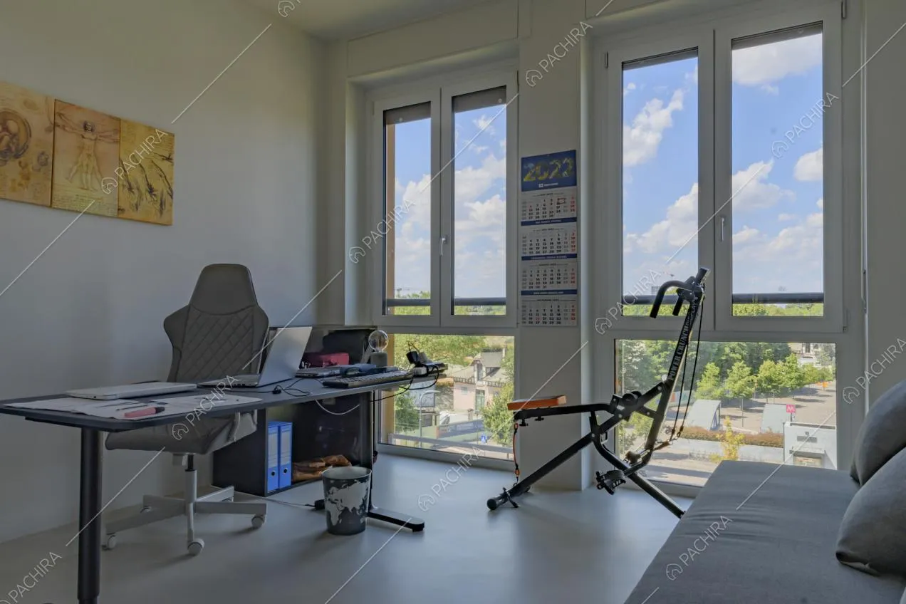 Studio con scrivania nera, divano e vista sul parco dalle ampie finestre