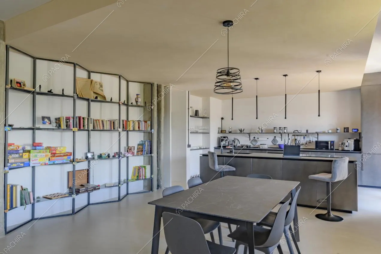 Tavolo da pranzo nero, libreria di design e vista sull'isola con sgabelli della cucina