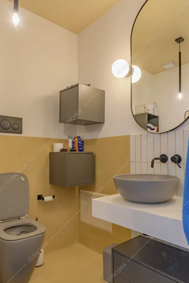 Bagno con pareti bianche e gialle e piastrelle rettangolari bianche
