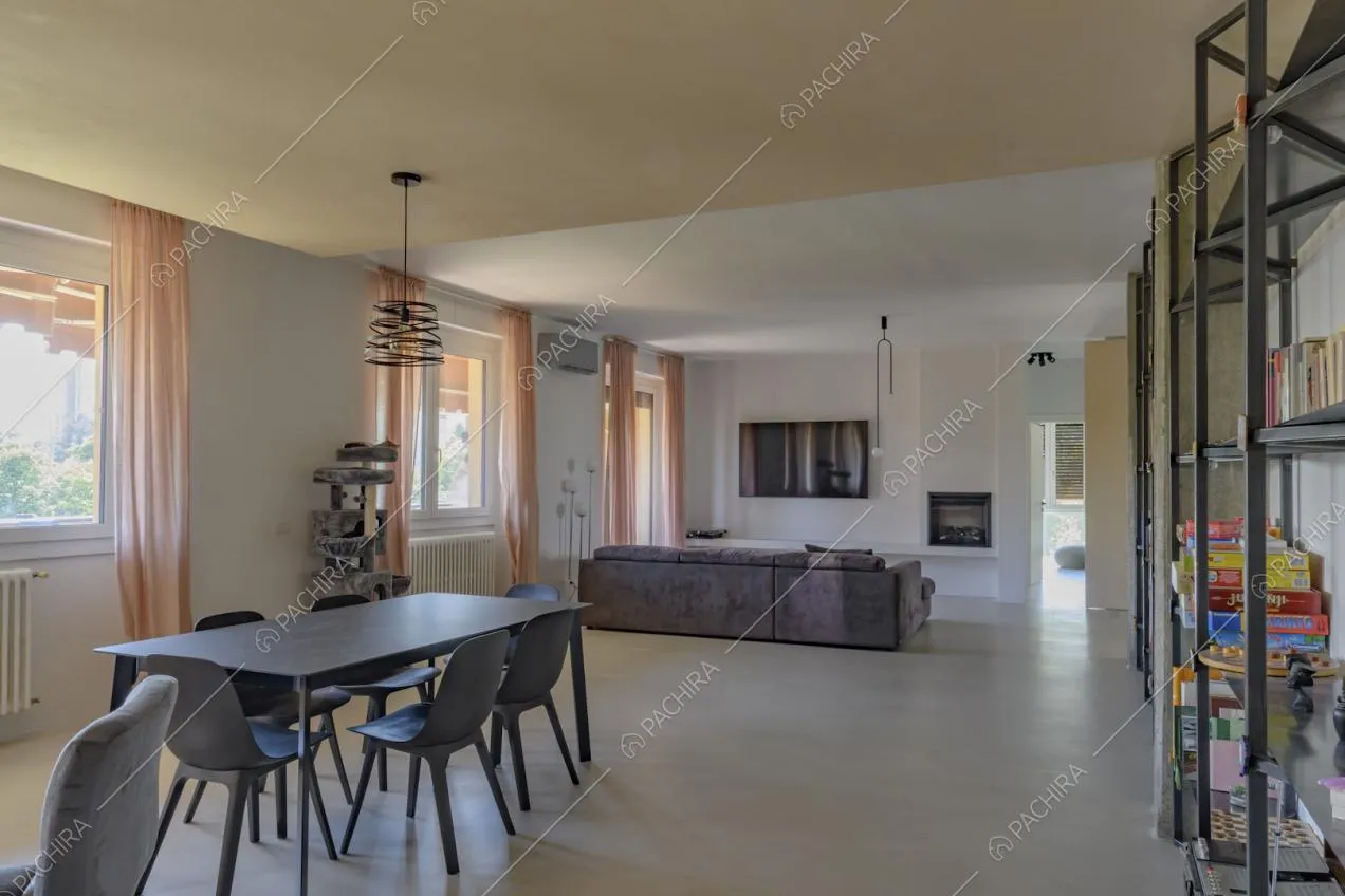Sala con pavimento bianco in cemento lisciato, tavolo da pranzo nero e divano