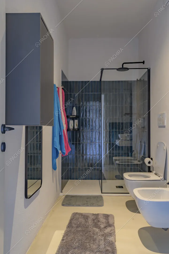 Bagno con servizi sospesi e ampio box doccia con piastrelle blu