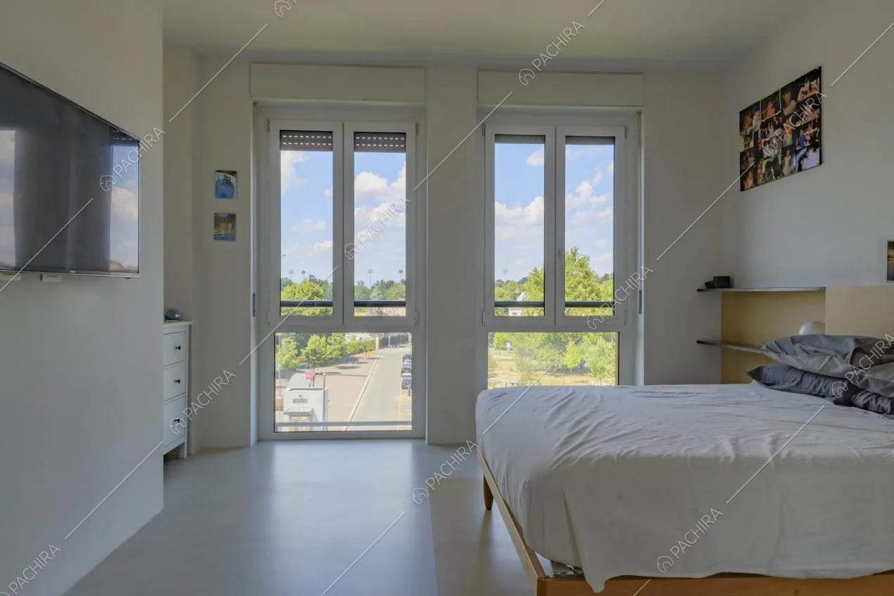 Ampia e luminosa camera da letto matrimoniale con pavimento bianco in cemento lisciato