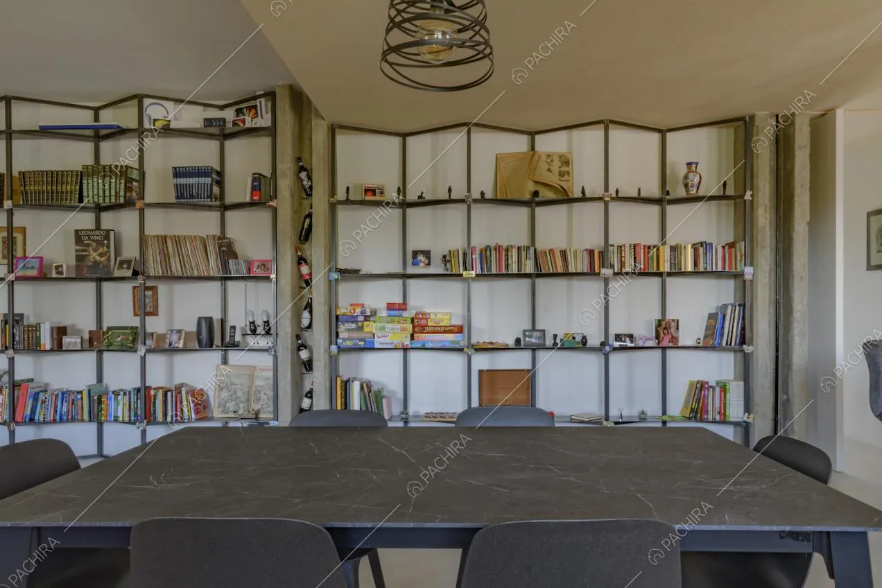 Tavolo da pranzo in marmo nero nella sala con libreria e lampadario di design