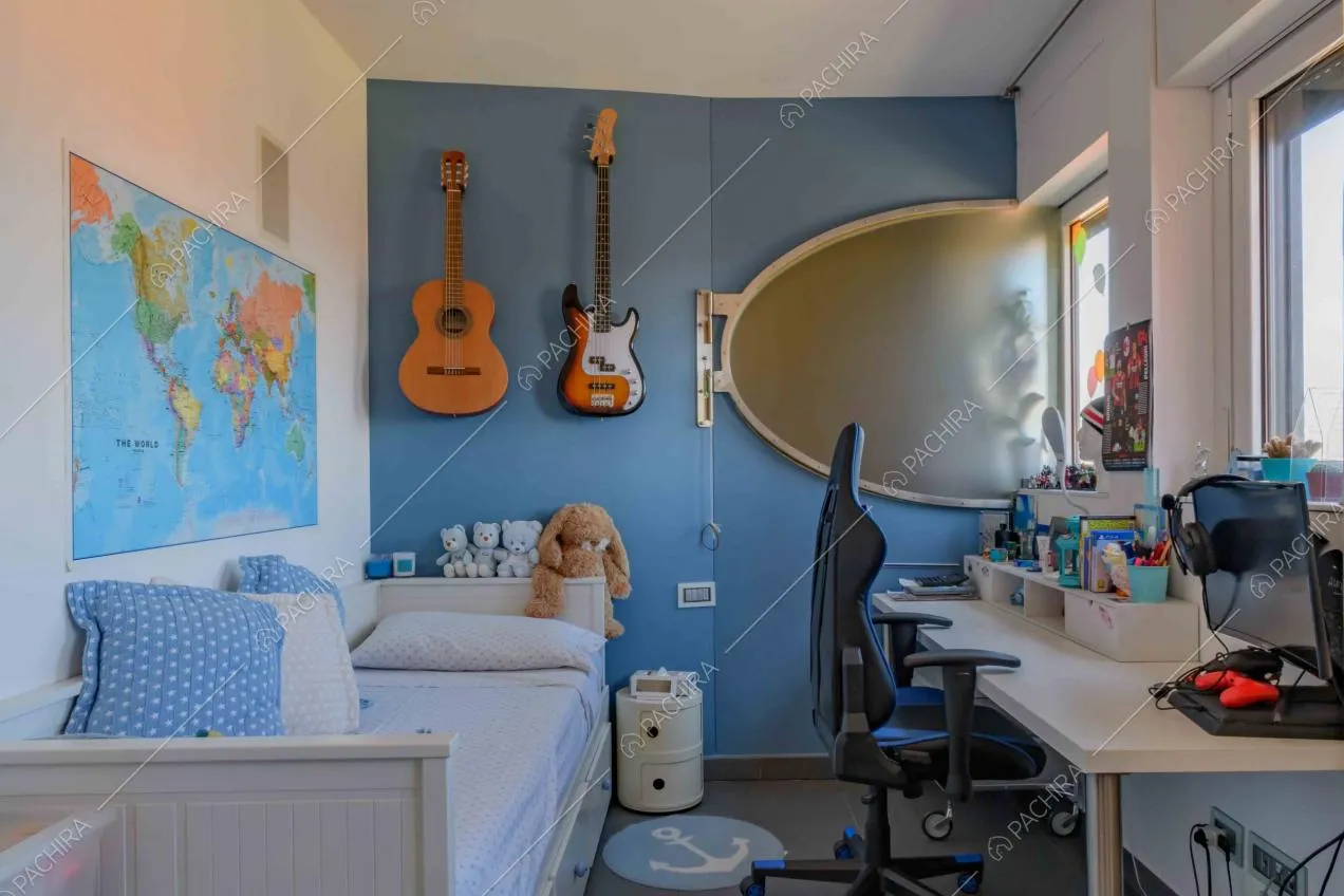 Camera da letto da ragazzi dalle pareti bianche e azzurre, con scrivania