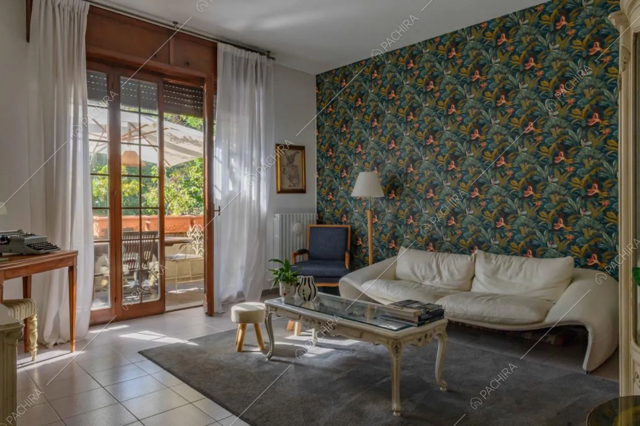 Salotto della dépendance con divano bianco, carta da parati e vista sul balcone