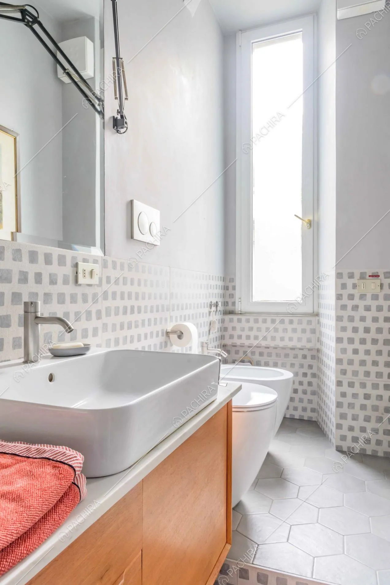 Luminoso bagno con pavimento in cementine grigie, doppio lavandino e carta da parati