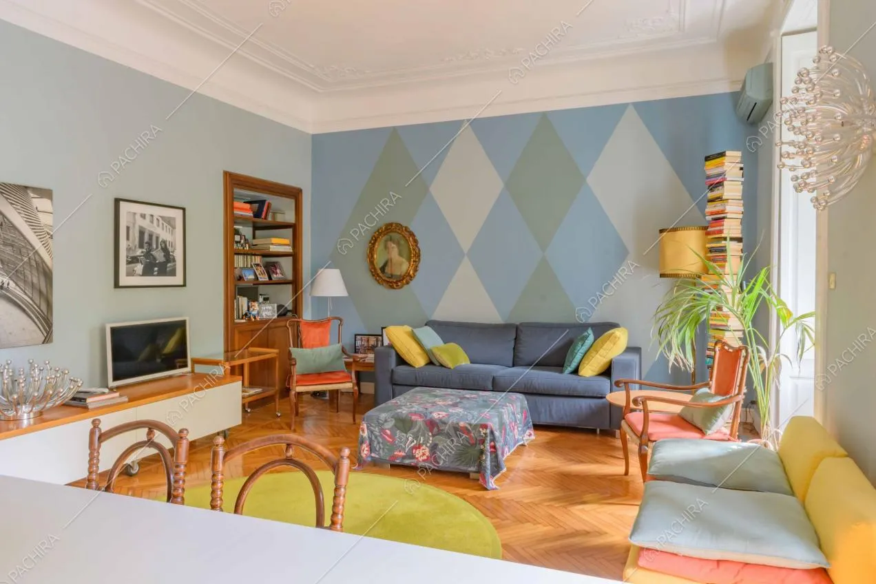 Tavolo da pranzo bianco nel luminoso salotto con pavimento in parquet e pareti sui toni dell'azzurro
