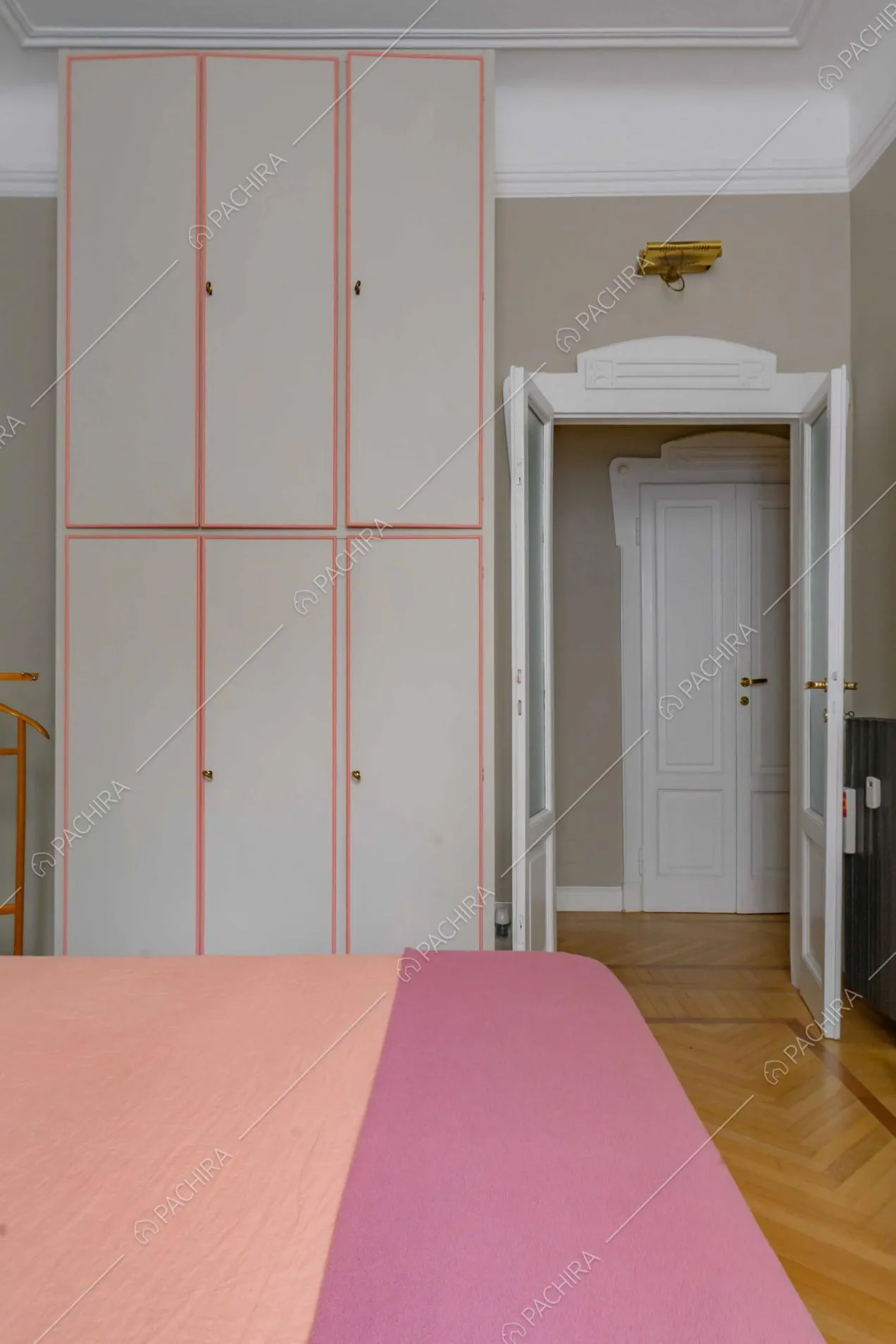 Armadi a muro e alti soffitti nella camera da letto in parquet a spina di pesce