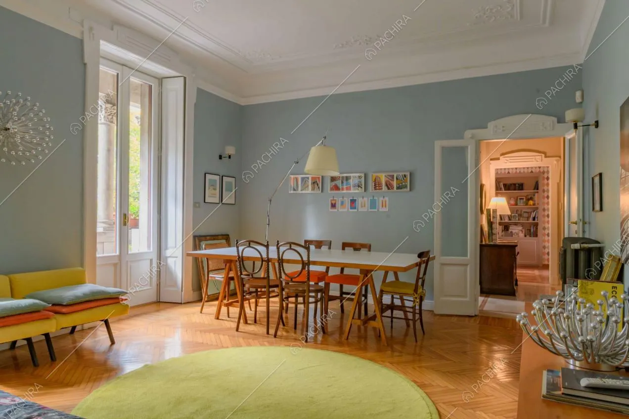 Luminosa e ampia sala con tavolo da pranzo, pareti azzurre e porte-finestre