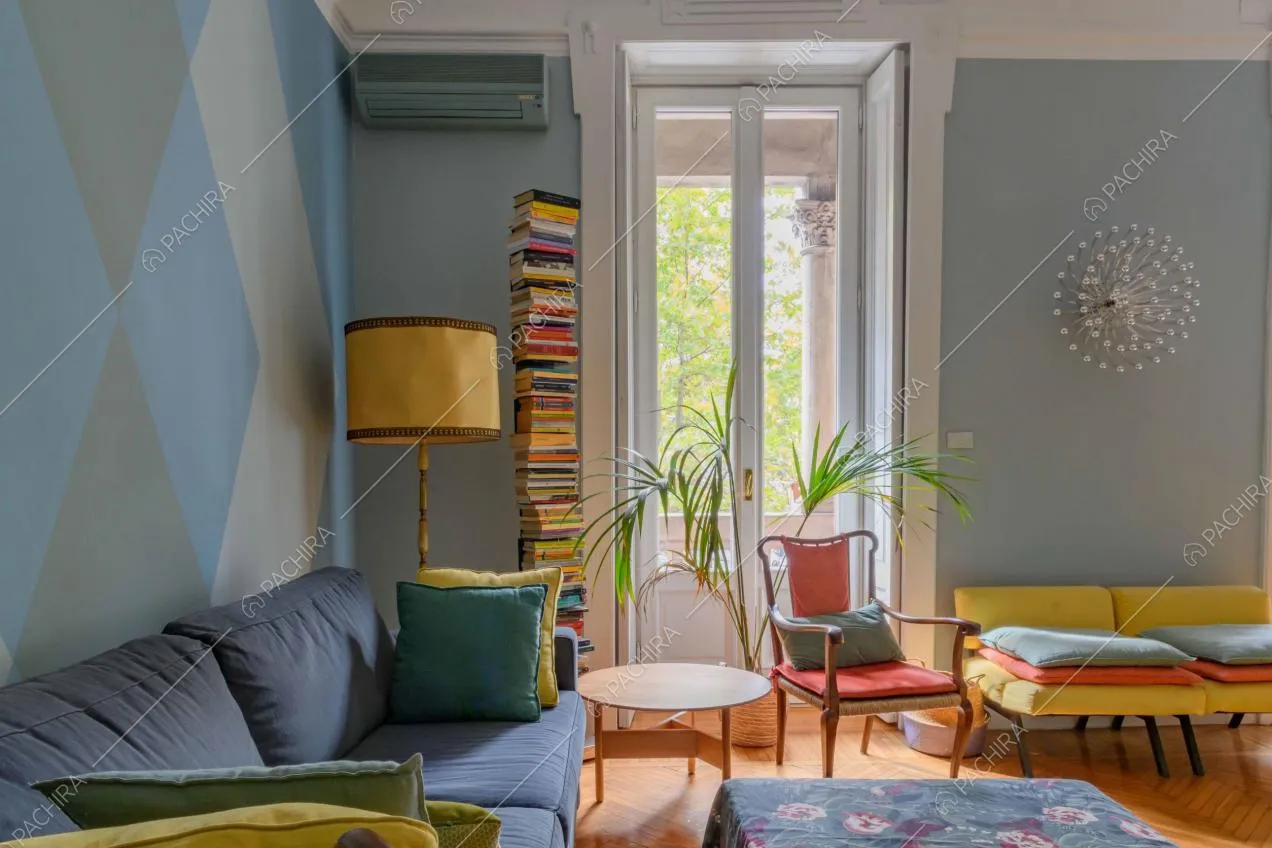 Divano blu e sedie di design nella sala dalle pareti azzurre e con porta-finestra