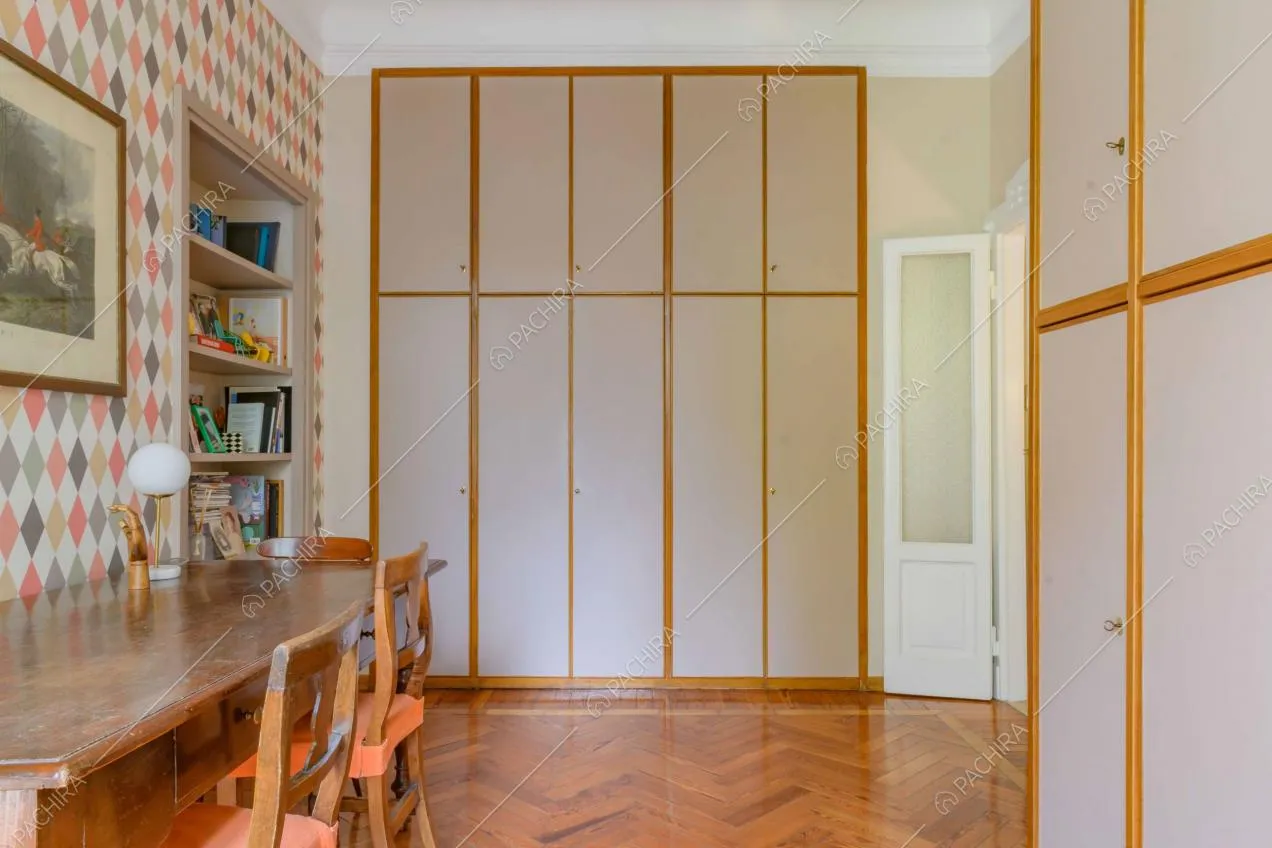 Camera con tavolo in legno, armadi a muro e pavimento in parquet a spina di pesce