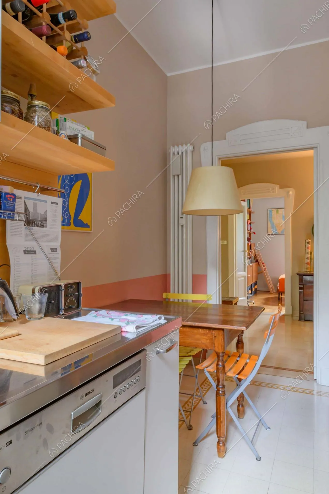 Cucina della location dalle pareti rosa e con tavolo da pranzo in legno