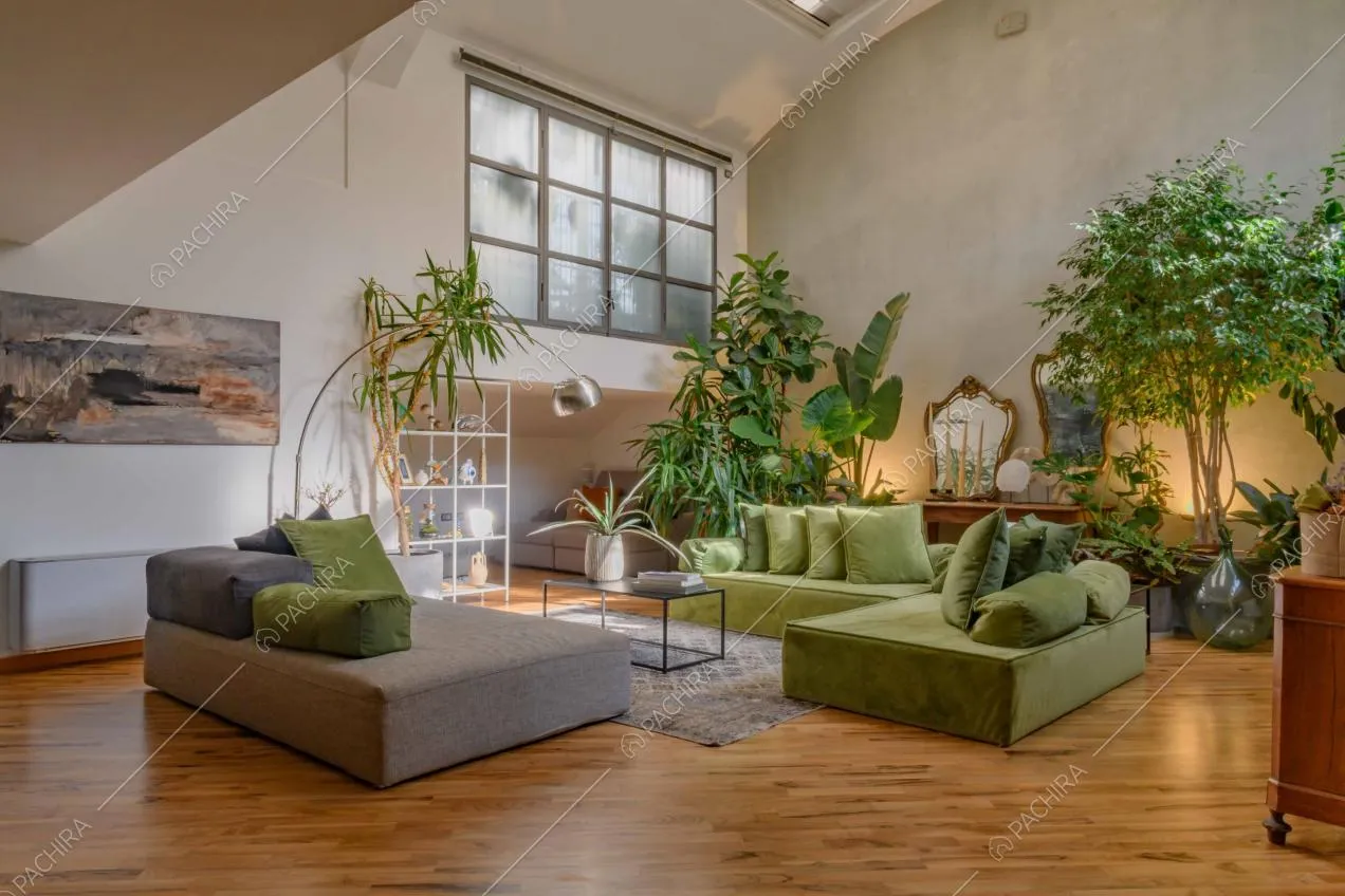 Salotto con pouf grigio, divano verde angolare e pavimento in parquet