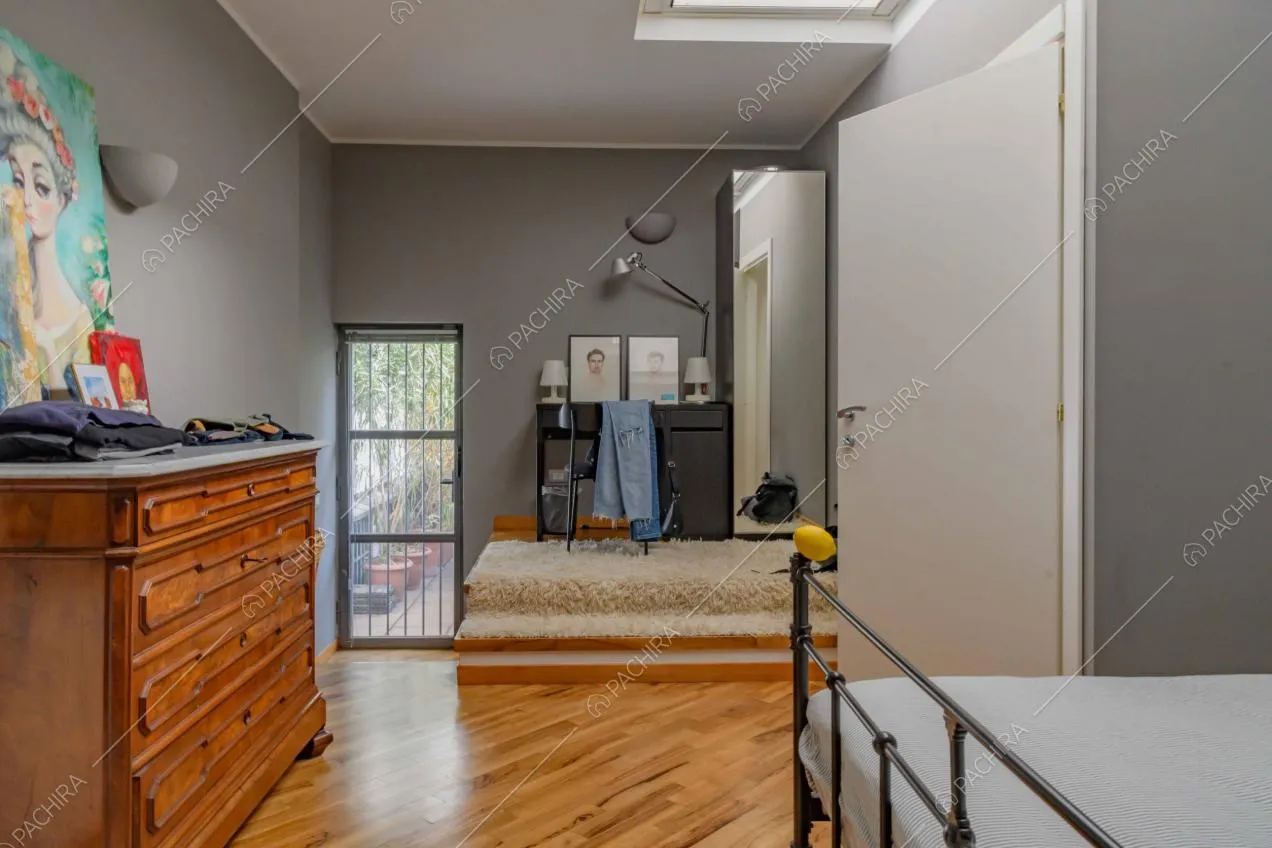 Camera da letto matrimoniale con pavimento in parquet, lucernario e accesso alla terrazza