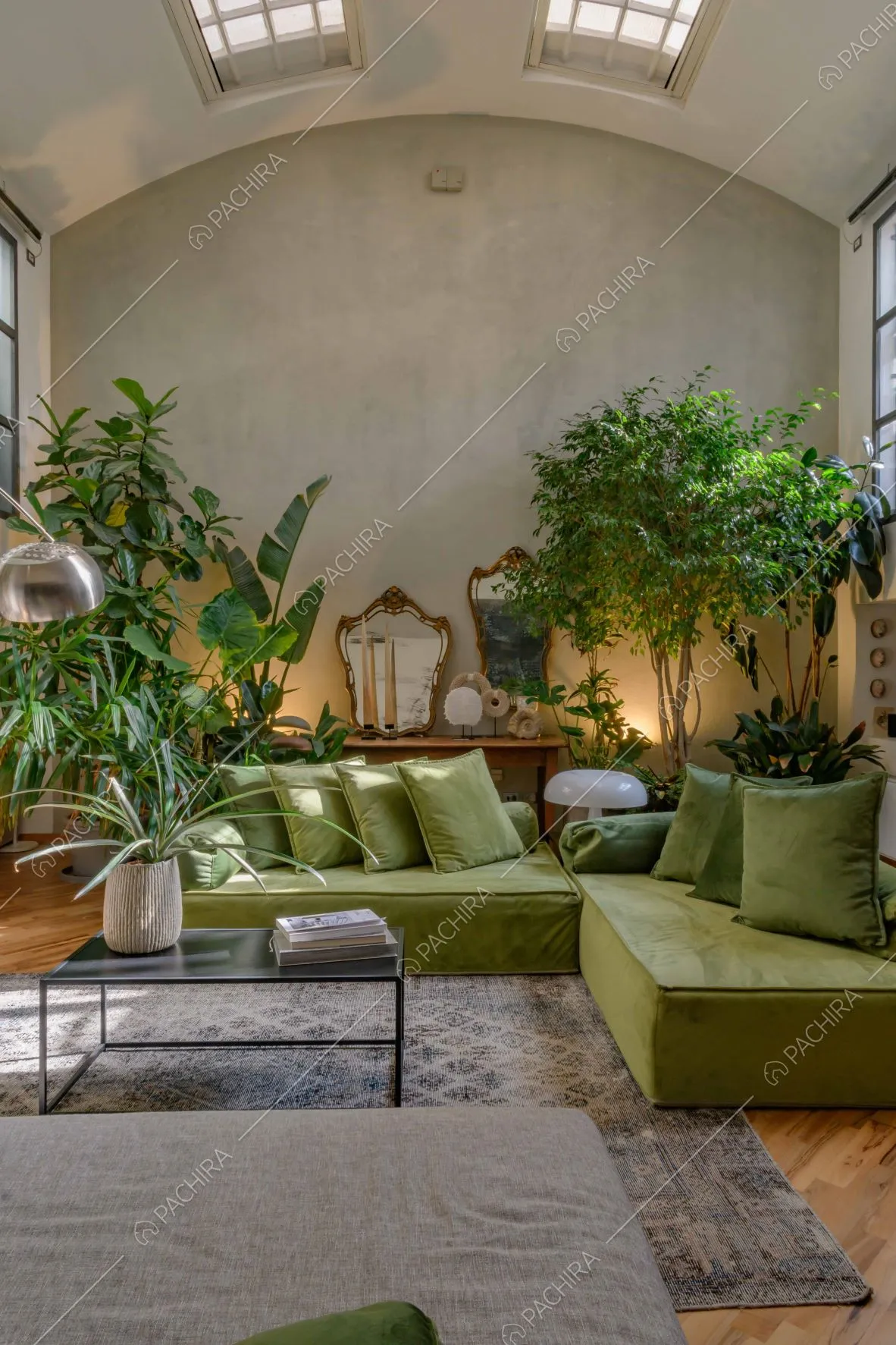 Luminoso salotto con piante, divano verde e pavimento in parquet