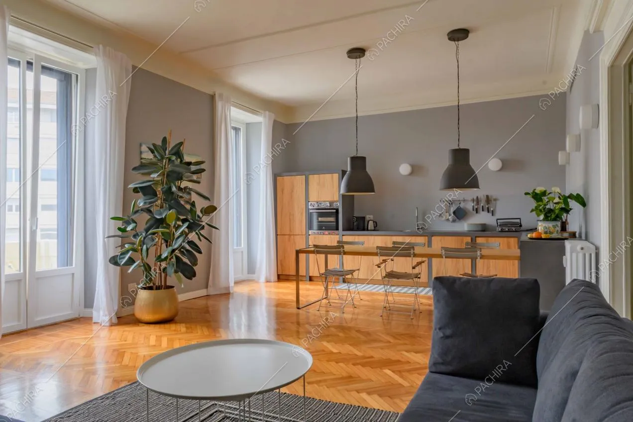 Dal divano nero vista sulla cucina con tavolo da pranzo e lampadari di design