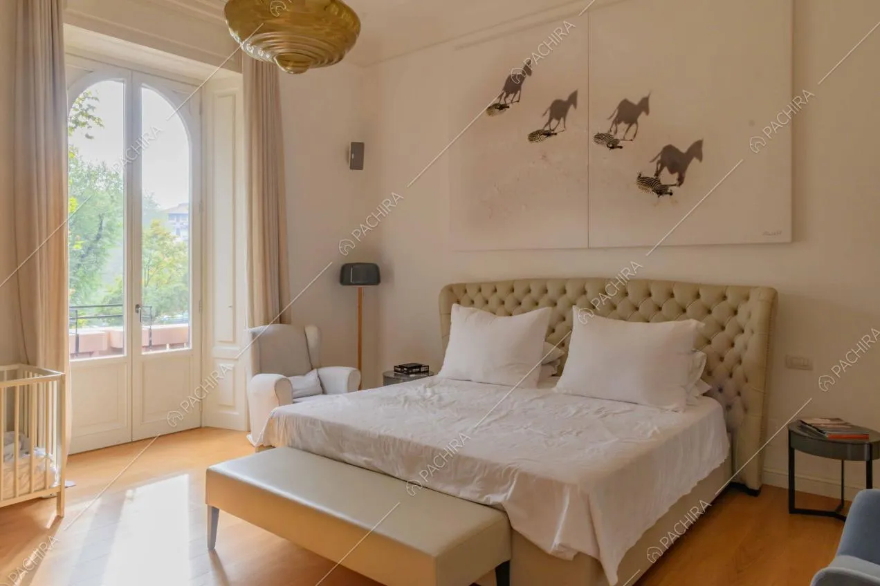 Camera da letto matrimoniale con pavimento in parquet, pareti bianche e balcone