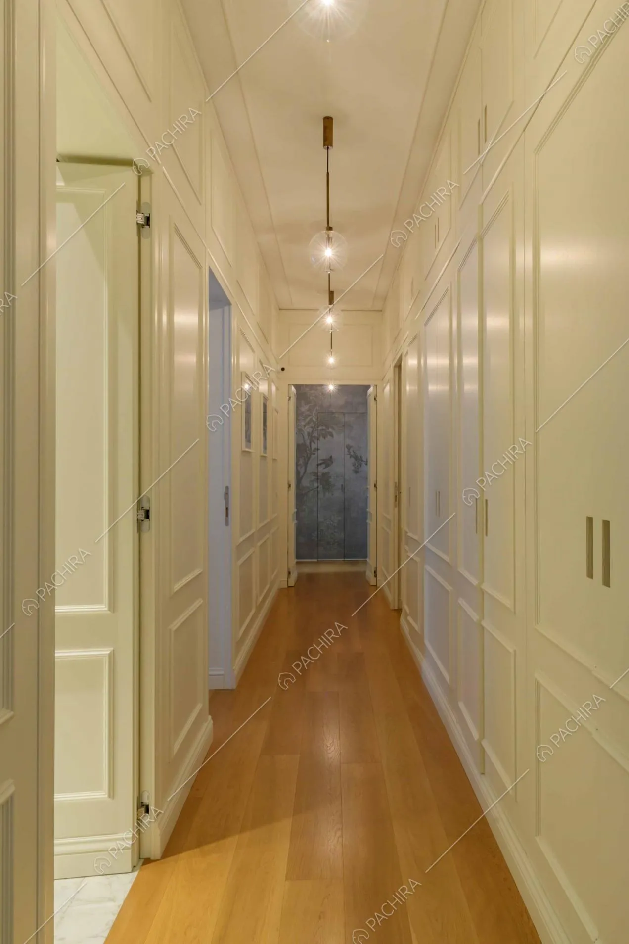 Corridoio dalle pareti bianche con boiserie e con pavimento in parquet
