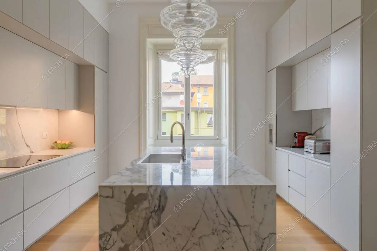 Cucina con isola in marmo, fornelli a induzione e pavimento in parquet