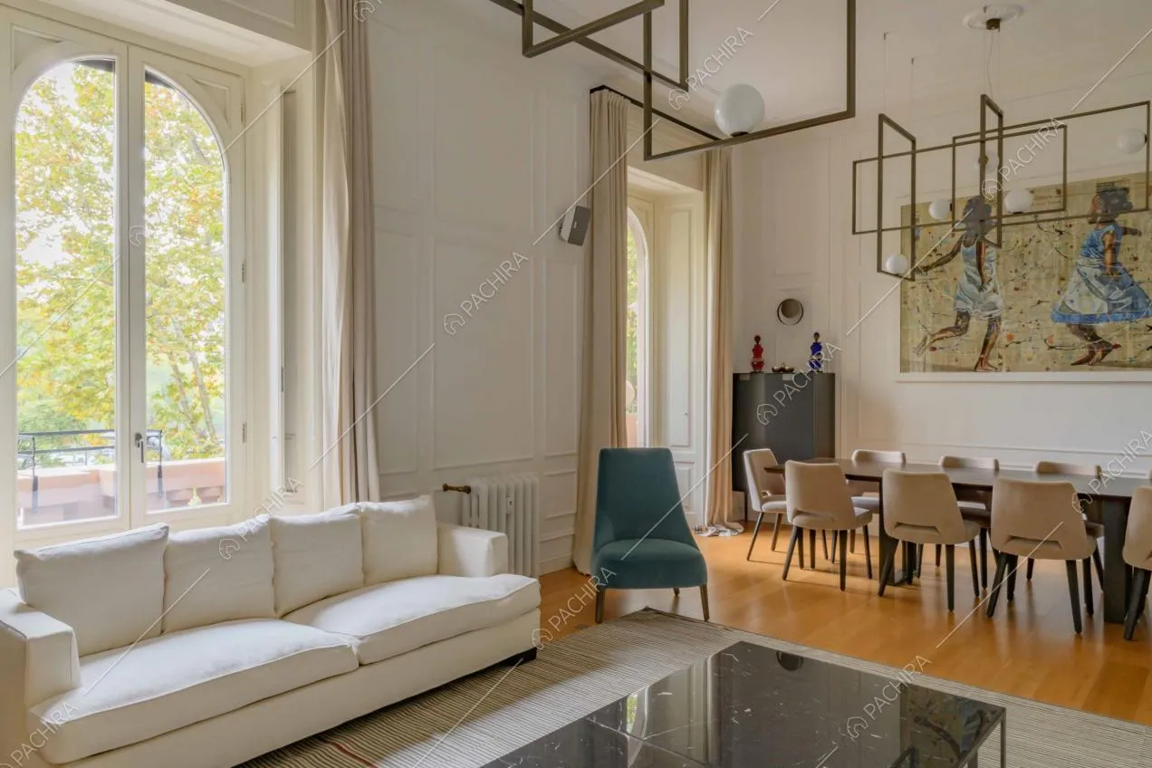 Salotto illuminato dalle ampie vetrate con lampadari di design e tavolo da pranzo