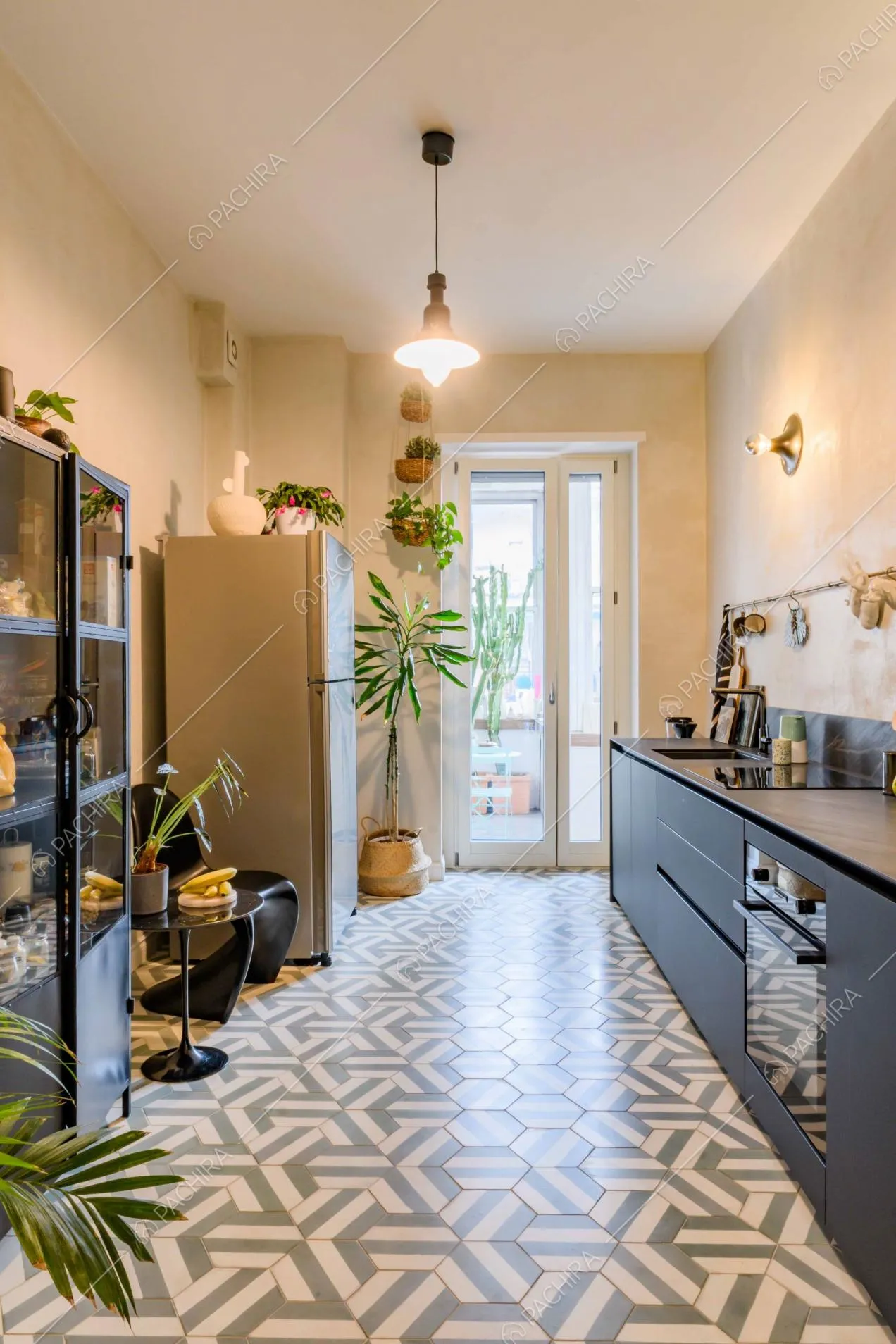 Cucina a muro con pavimento in cementine a forme geometriche e porta-finestra che conduce alla veranda