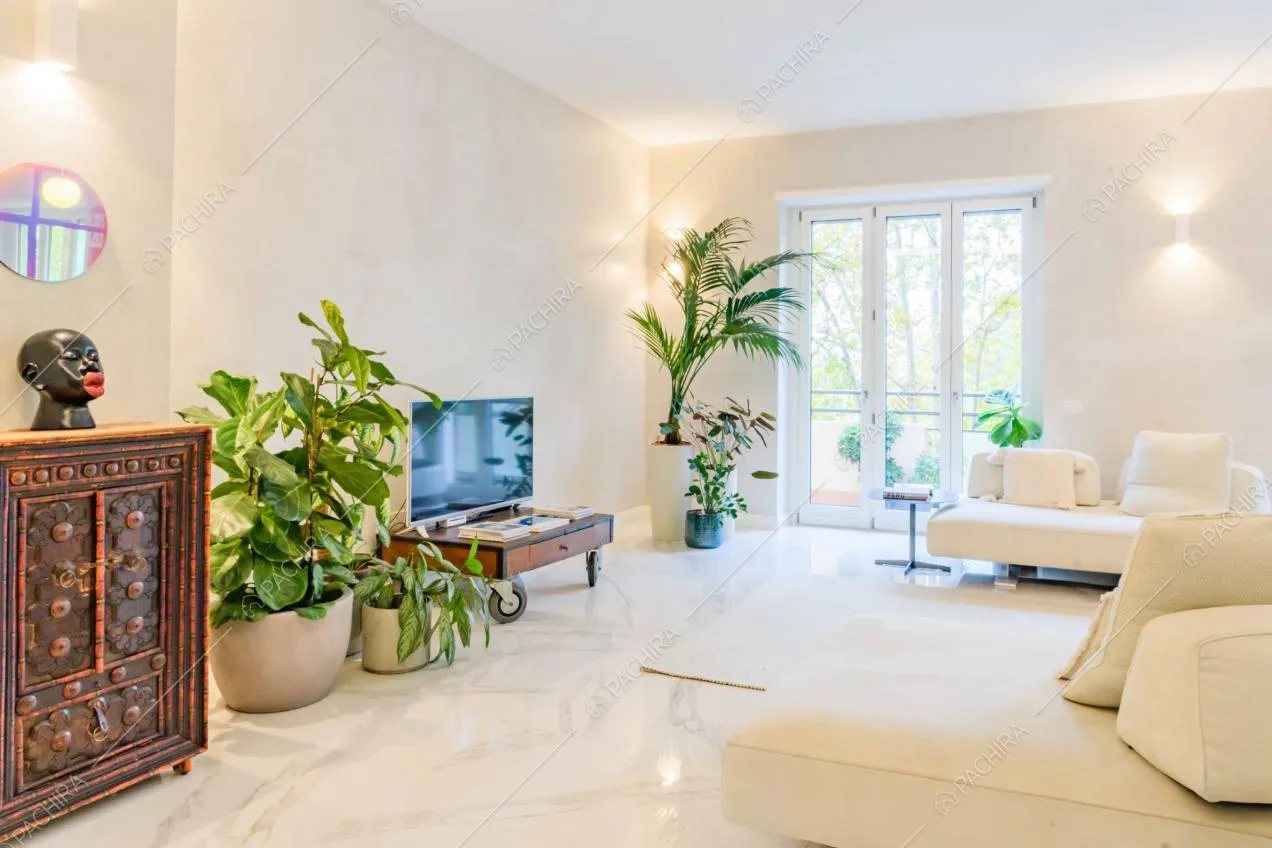 Divani bianchi nella sala con pavimento in marmo bianco illuminata dalle porte-finestre