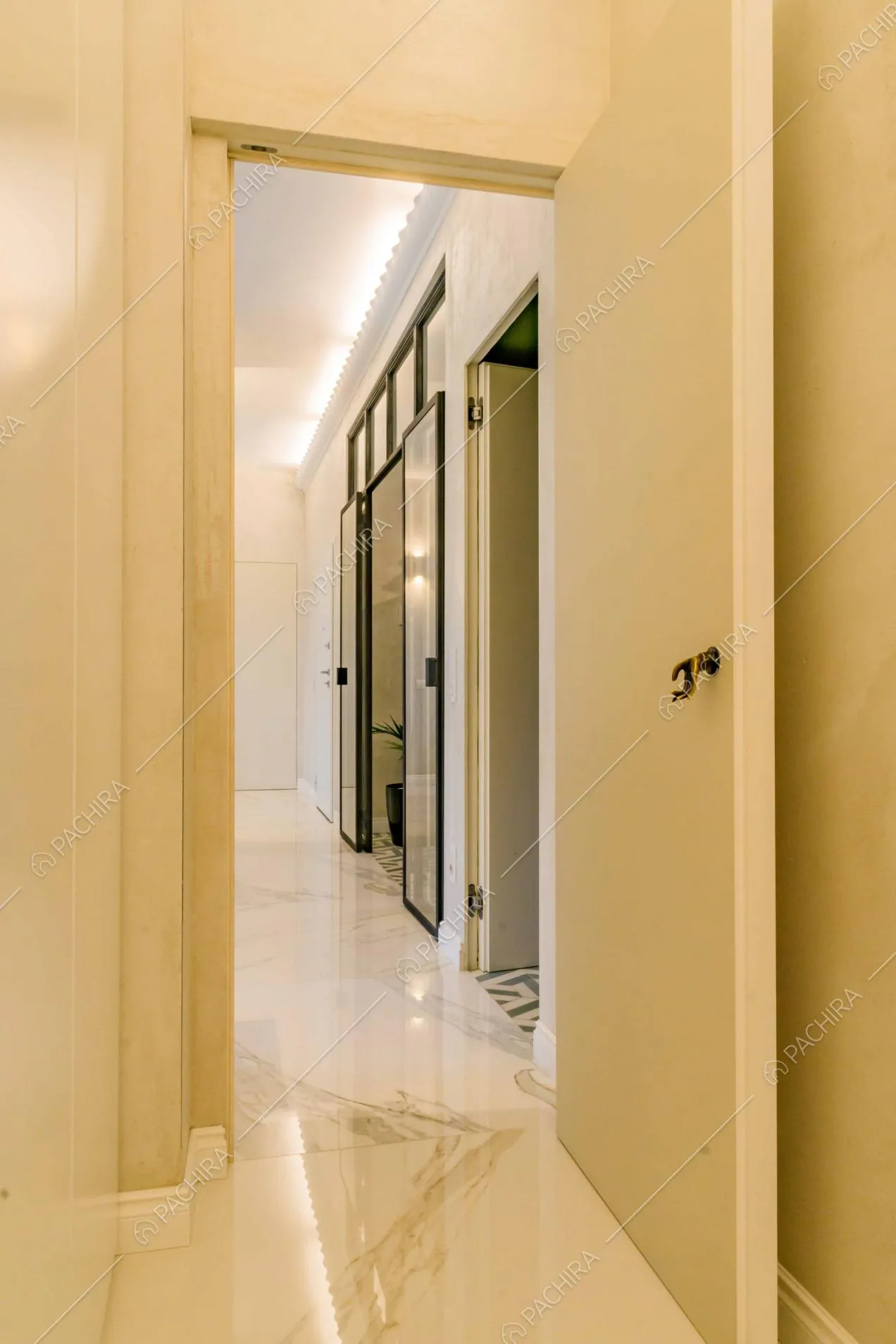 Corridoio con pavimento in marmo e vista sulla porta a vetri in stile industriale che porta alla cucina