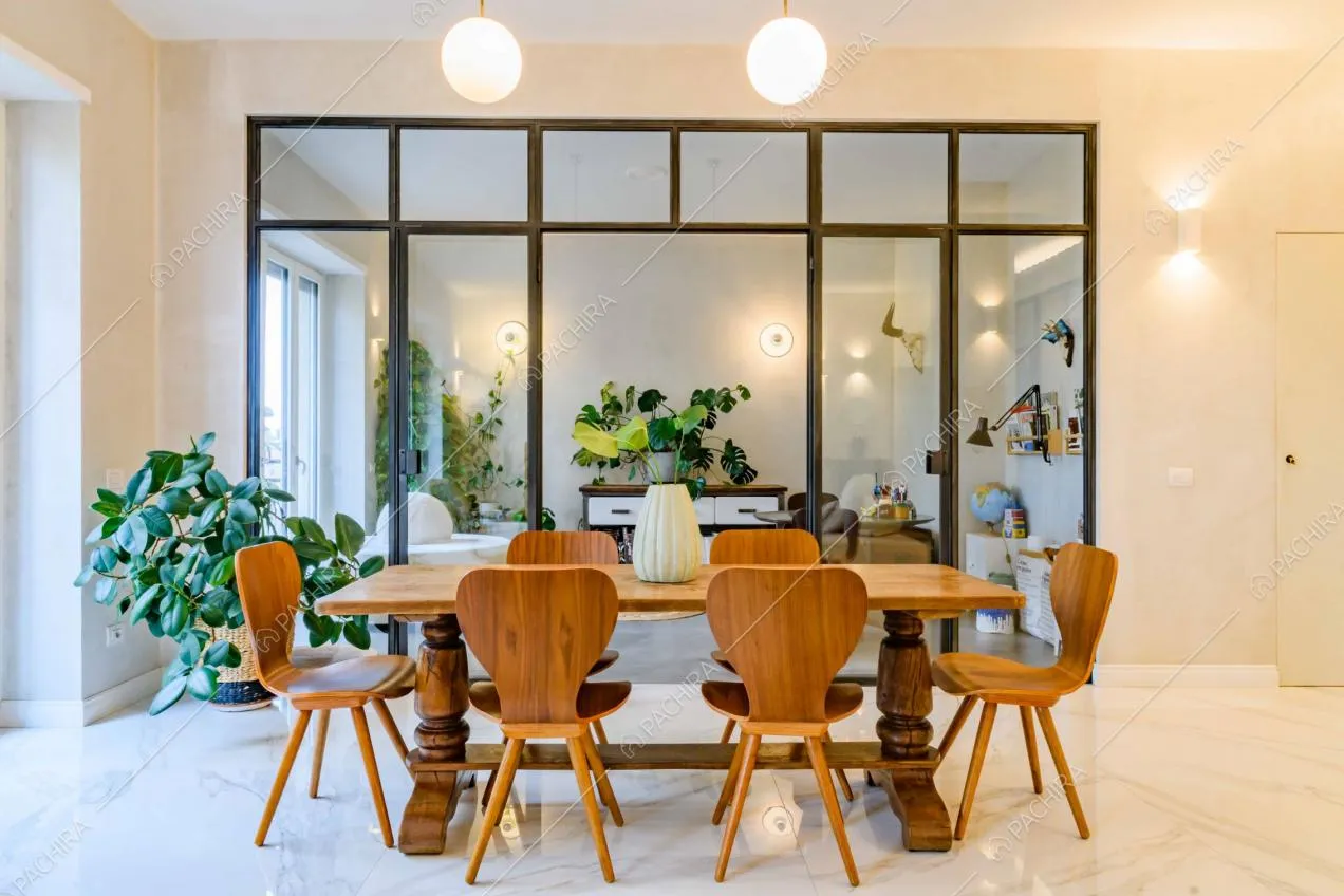Tavolo da pranzo in legno nella sala con pavimento in marmo e vista sul salotto separato da una porta a vetri