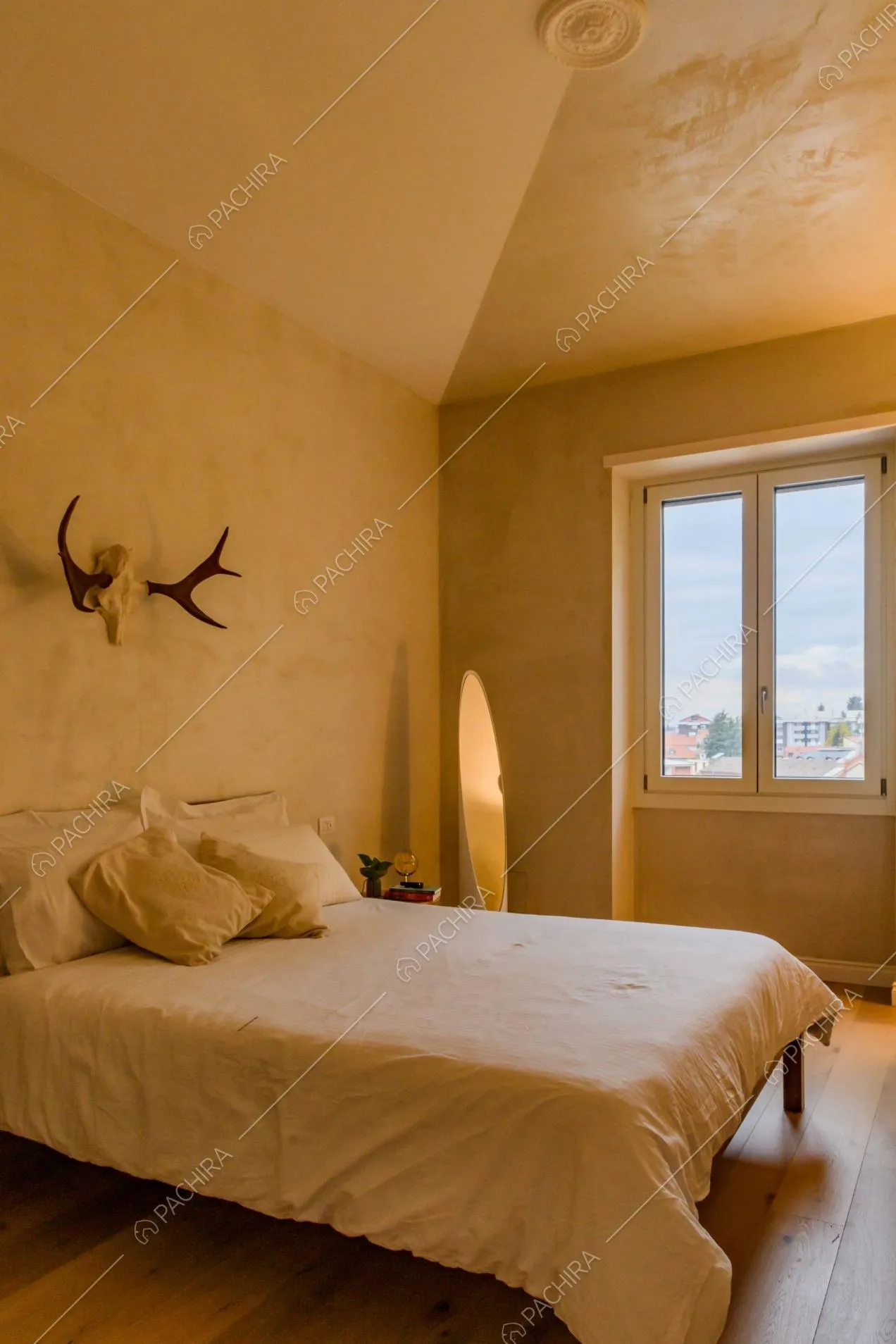 Letto matrimoniale nella camera con pavimento in parquet e corna di cervo alla parete