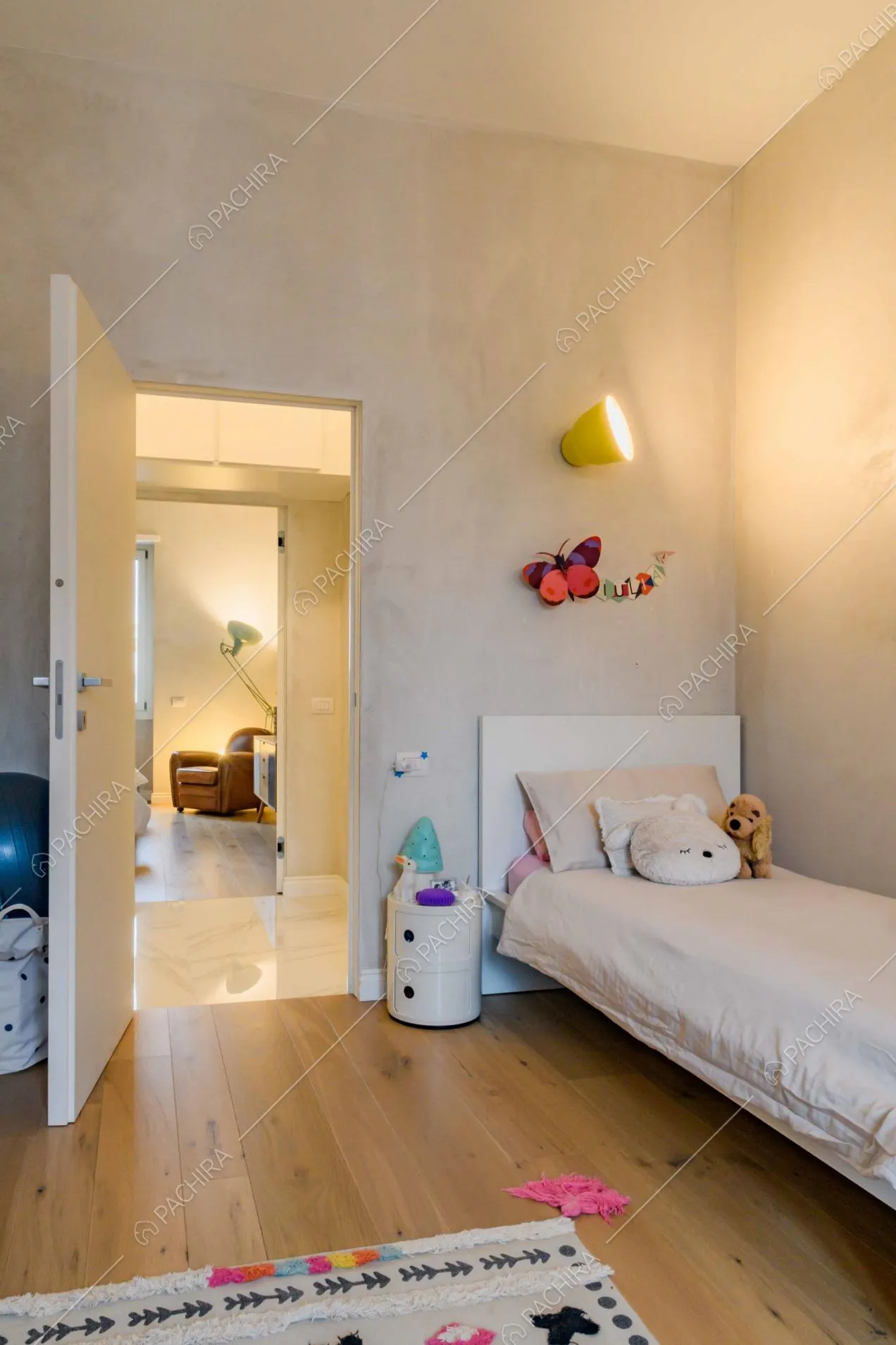 Dal letto della stanza da bambini vista sulla camera da letto con poltrona marrone
