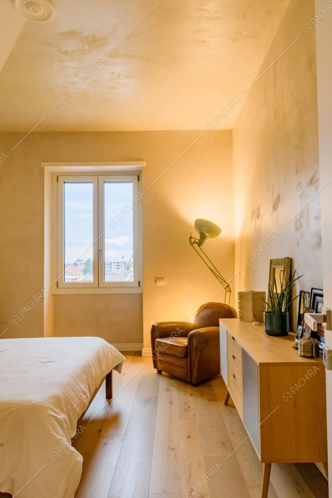 Camera da letto matrimoniale in stile minimal con pavimento in parquet e poltrona marrone in pelle