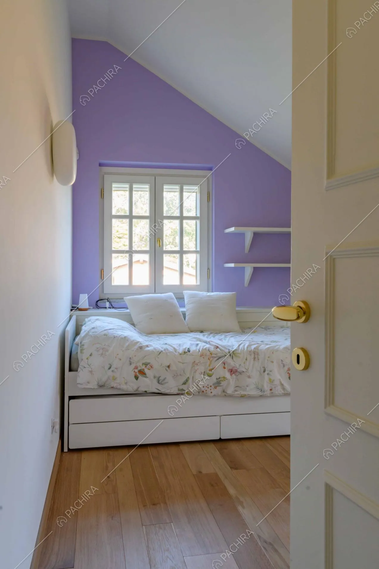 Dalla porta d'ingresso vista sulla camera da letto con pavimento in parquet e parete viola
