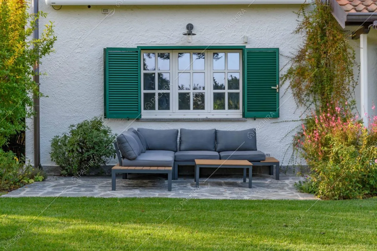 Divano grigio da esterni con divanetti, pavimentazione in lastre di pietra e vista sugli esterni della villa