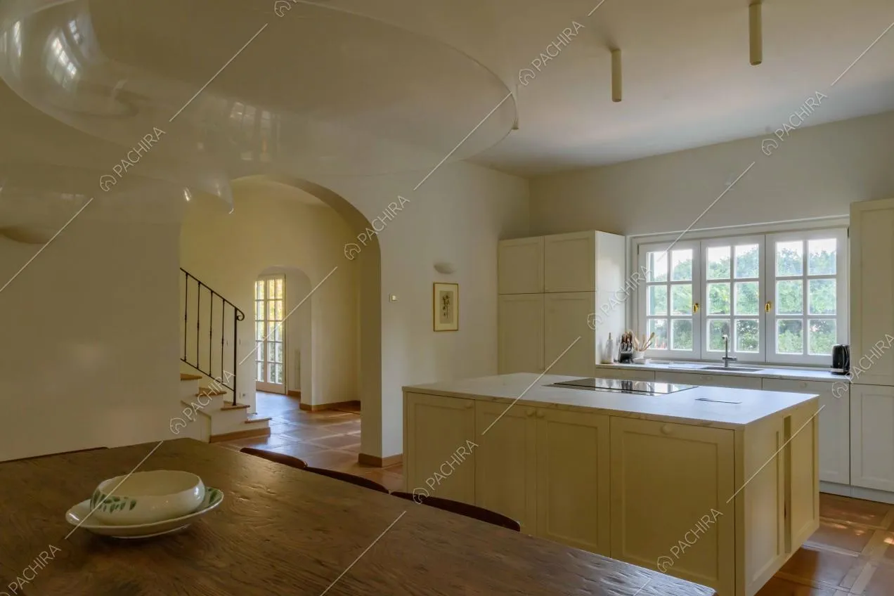 Dal tavolo da pranzo in legno della cucina vista sull'ingresso con pavimento in cotto e sull'isola con fornelli a induzione