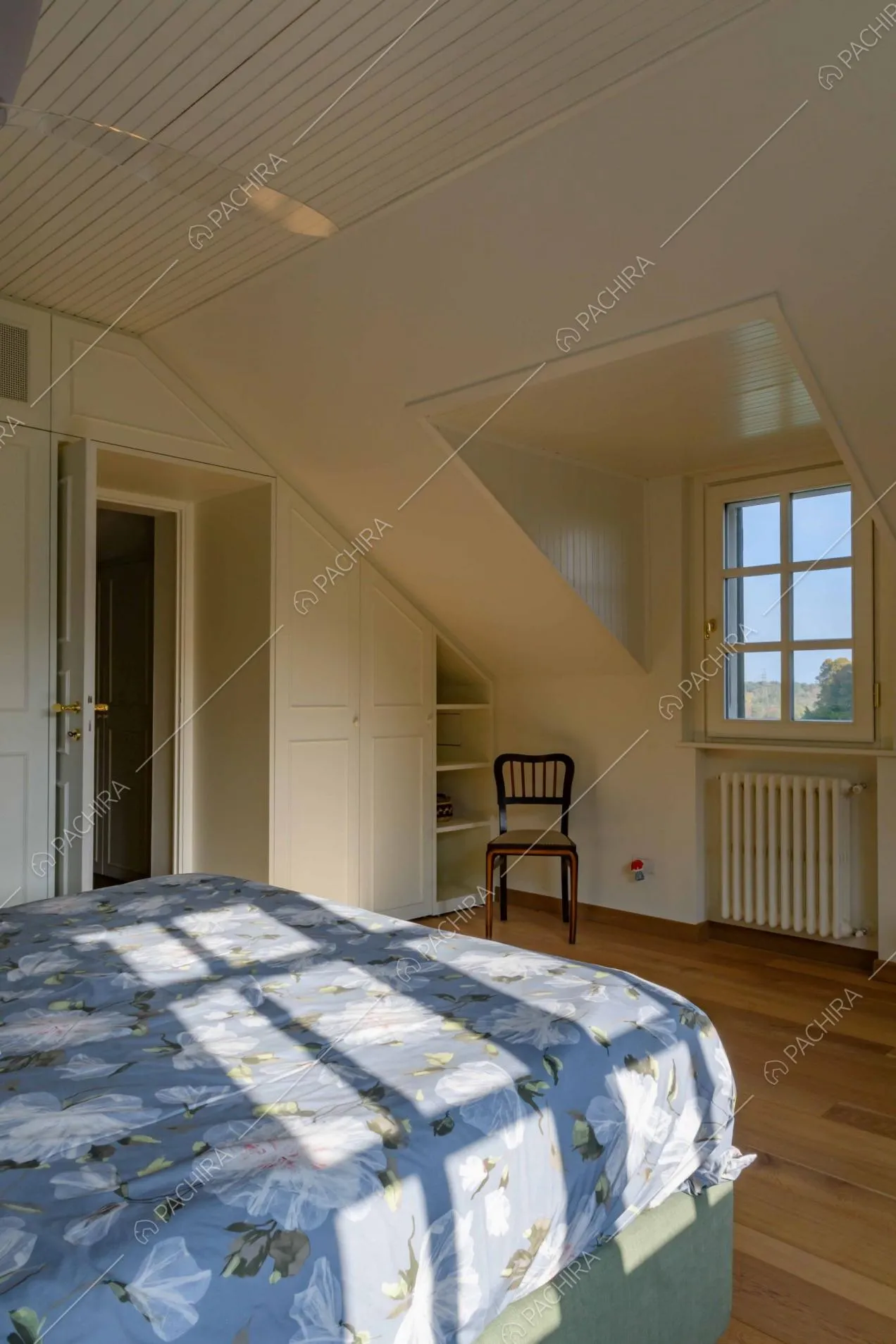 Luminosa camera da letto matrimoniale con pavimento in parquet e scorcio sul corridoio