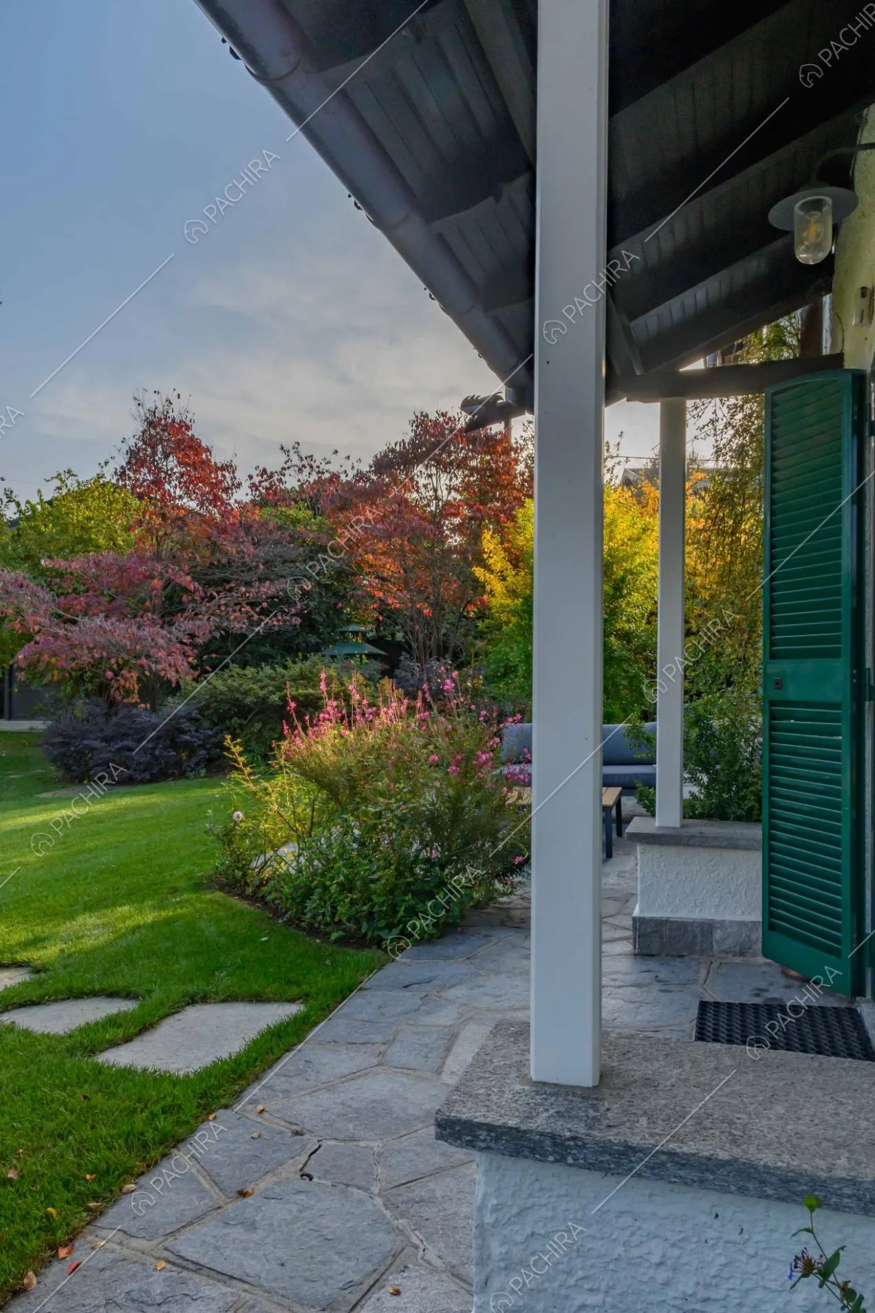 Portico con pavimentazione in lastre di pietra, colonne bianche e vista sullo splendido giardino