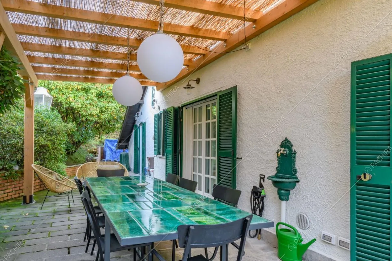 Veranda con tavolo dal piano da lavoro verde e sedie nere in metallo