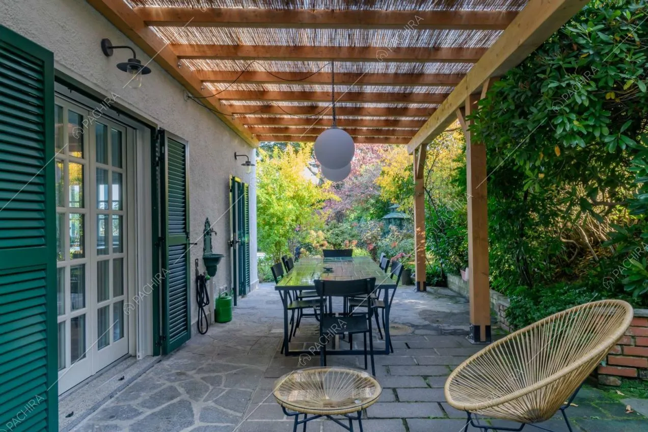 Veranda con sedie, tavolo da pranzo da esterni e pavimentazione in pietra