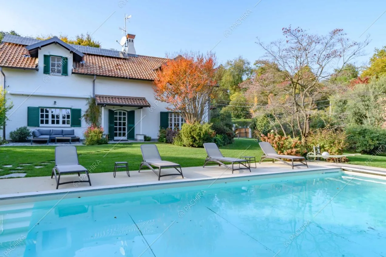 Grande piscina nello splendido giardino della villa con alberi, letti ed esterni della villa