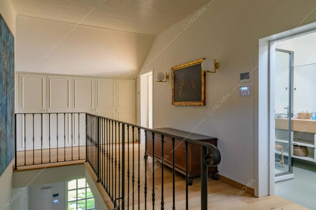 Pavimento in parquet e armadi bianchi con boiserie al piano superiore con vista sull'ingresso