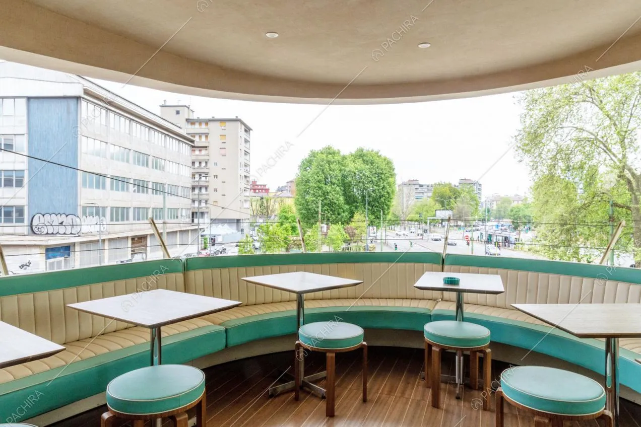 Panca in pelle, tavolini e sgabelli sulla terrazza coperta con pavimento in parquet