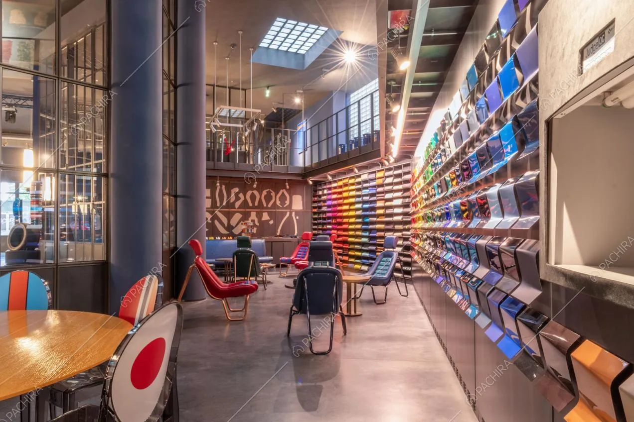 Sala con poltrone di design colorate, pavimento in cemento lisciato, lucernario e grandi vetrate in stile industriale