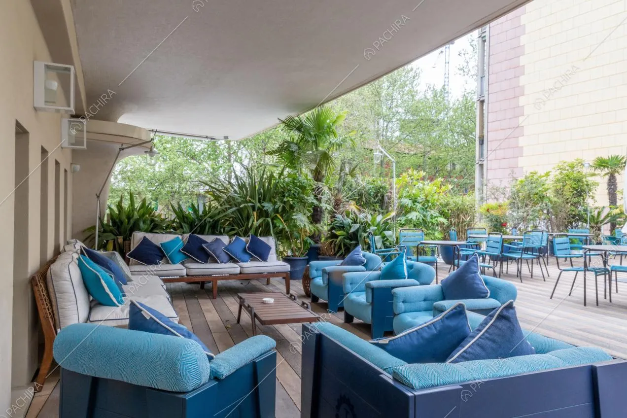 Grande terrazza con pavimento in parquet, divanetti e sedie blu