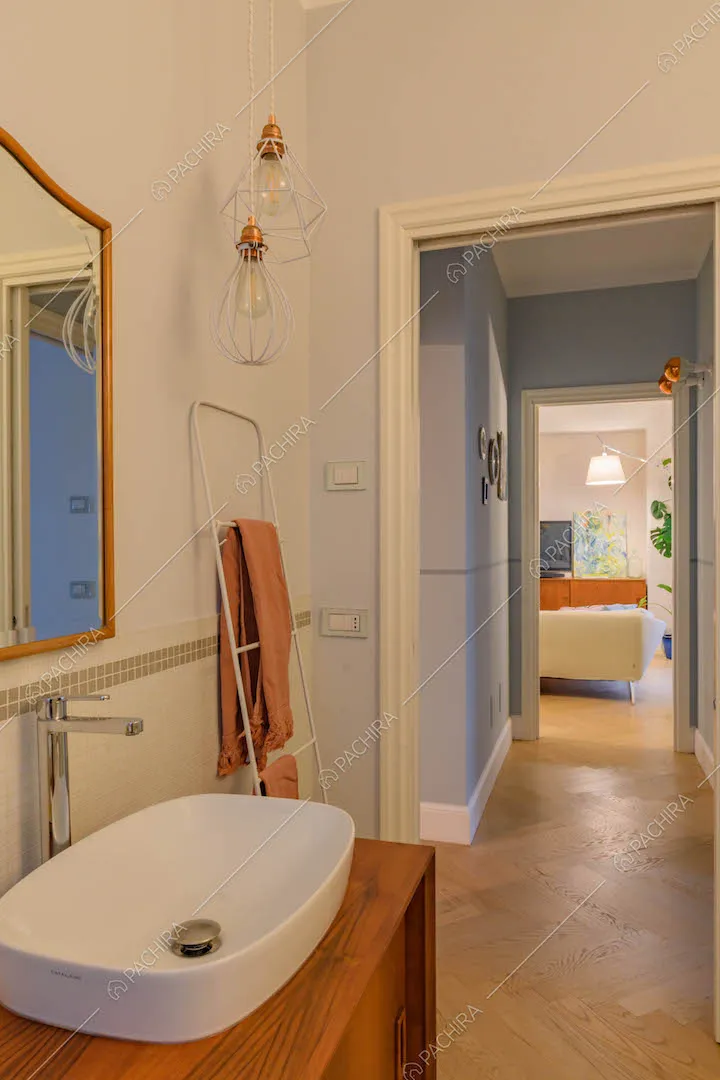 Bagno con mobile in legno, pareti azzurre e pavimento in parquet a spina di pesce