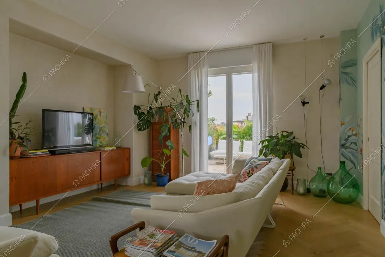 Sala con divani bianchi, pavimento in parquet a spina di pesce e porta-finestra per accedere alla terrazza