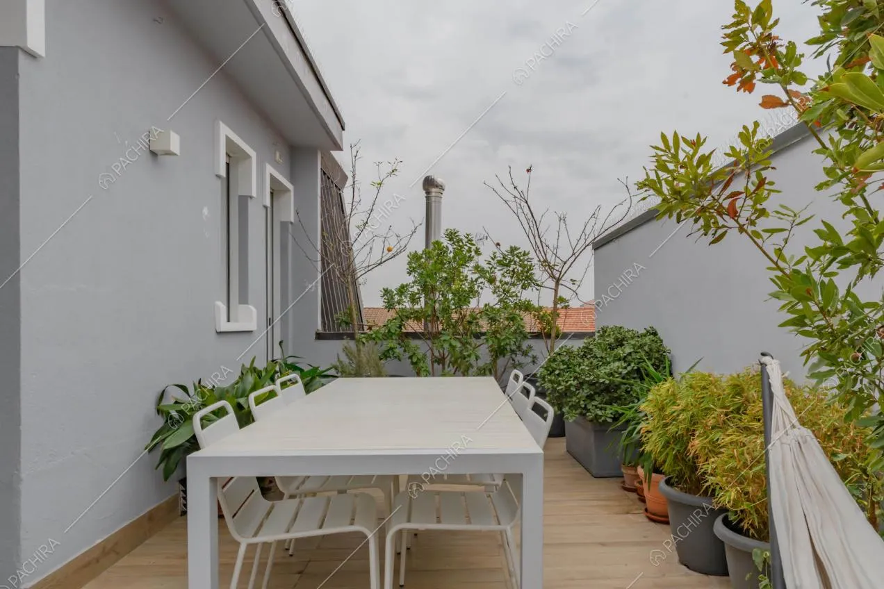 Terrazza con tavolo da pranzo e sedie bianche, pavimento in parquet e vista sullo skyline