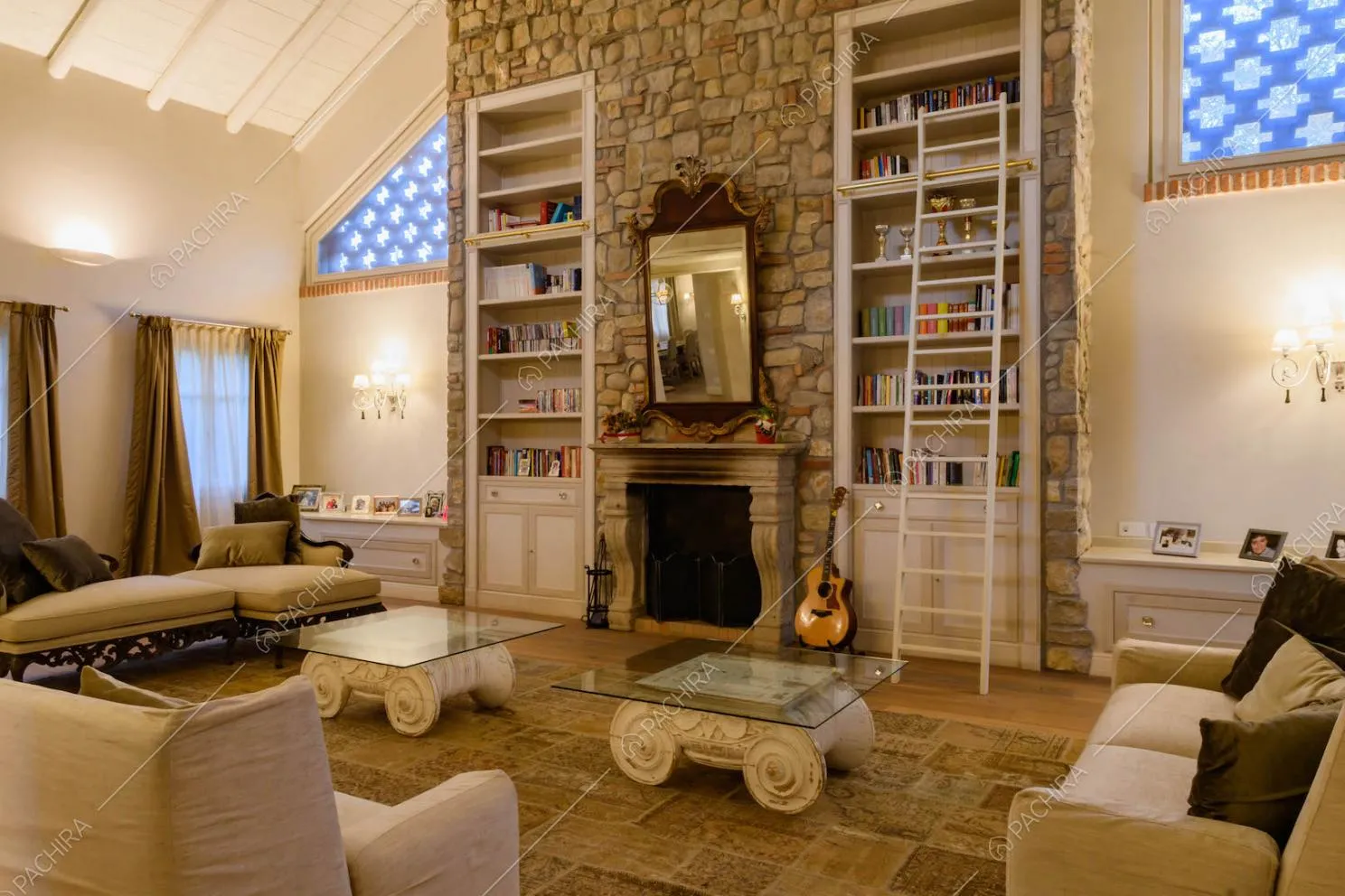 Salotto con pavimento in parquet, alto soffitto, parete in pietra a vista con camino e soffitto in travi in legno bianco