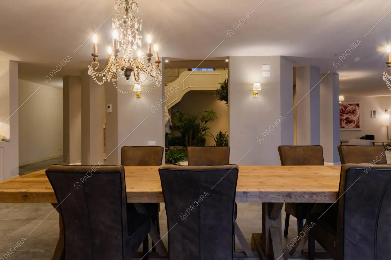 Sala da pranzo con lampadari in stile classico, tavolo in legno e vista sul giardino d'inverno