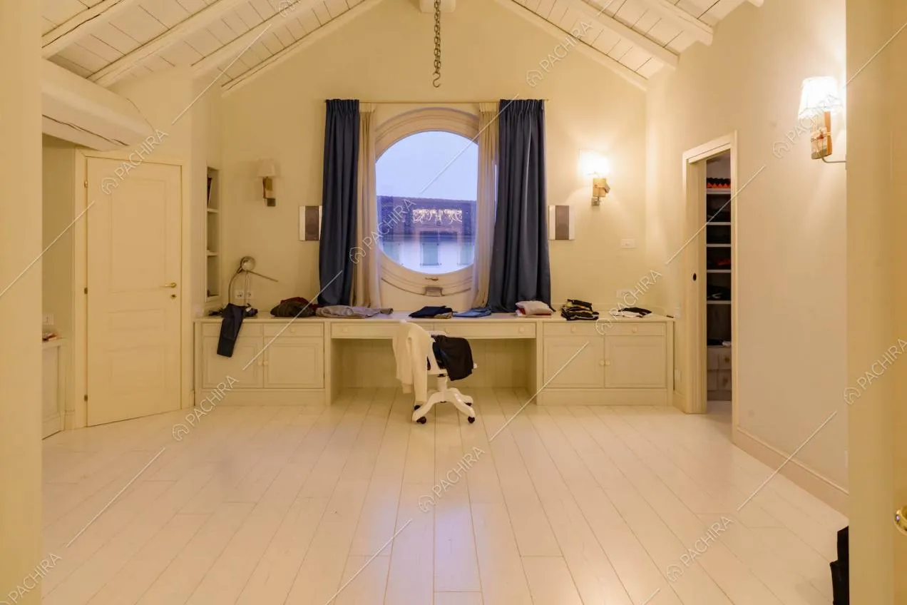Nella camera da letto parquet bianco, travi in legno a vista e scrivania