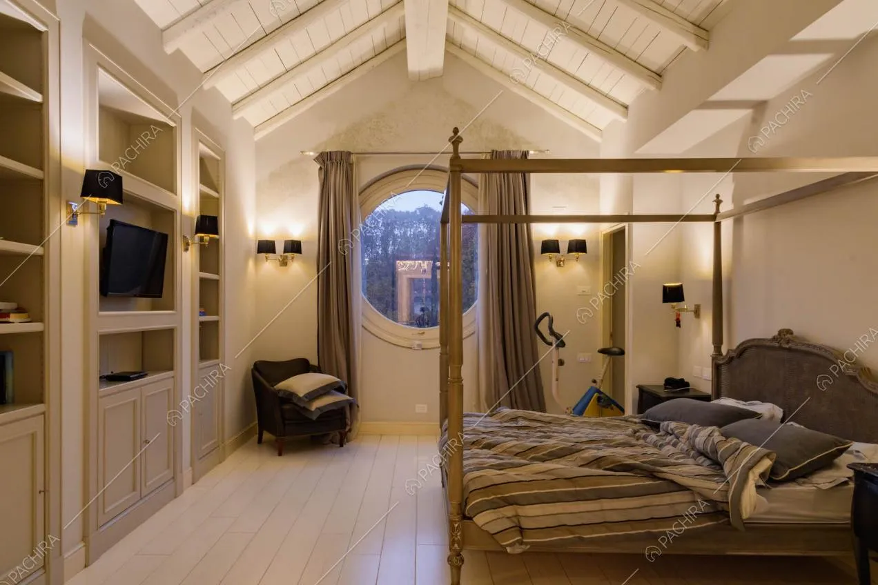 Letto matrimoniale a baldacchino nella camera con parquet bianco e finestra a oblò
